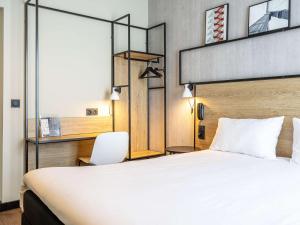 una habitación de hotel con una cama grande y una silla en ibis Paris Boulogne Billancourt, en Boulogne-Billancourt