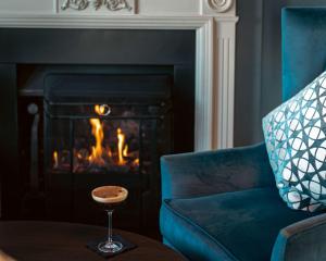 a living room with a blue chair and a fireplace at DoubleTree by Hilton London – Docklands Riverside in London