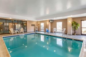 una piscina en una habitación de hotel con sillas y mesas en Comfort Suites South Point - Huntington en Burlington