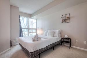 a bedroom with a large white bed with a window at RivetStays - The Yonge in Toronto