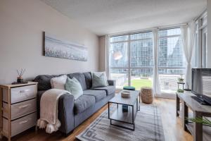 a living room with a gray couch and a large window at RivetStays - The Yonge in Toronto