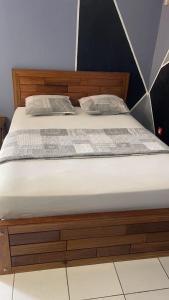 a wooden bed with two pillows on it at Ouest Nelis Lodge in Saint-Laurent du Maroni