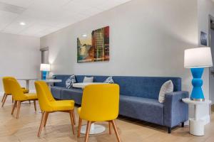 Comfort Inn & Suites Danbury-Bethel في دانبري: غرفة معيشة مع أريكة زرقاء وكراسي صفراء