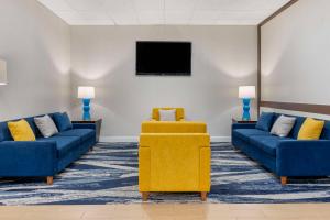 Comfort Inn & Suites Danbury-Bethel في دانبري: غرفة انتظار مع اثنين من الأرائك الزرقاء وتلفزيون