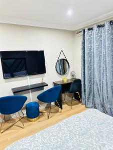 1 dormitorio con 2 sillas azules y TV en Mayberry Heights, en Alberton