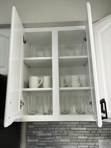 um armário branco com copos e pratos em Newly Renovated Elmhurst Home! em Elmhurst