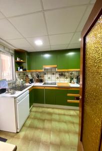 a green kitchen with white appliances and green cabinets at Habitación My Home Alicante in Alicante