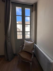 einen Stuhl mit Kissen in einem Zimmer mit Fenster in der Unterkunft Pézenas Centre - Charme village - Plage 15 mn in Pézenas