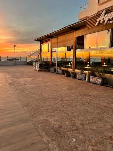 a building on the beach with a sunset in the background at The blue pearl-Sensational beach apartment in Aourir in Agadir