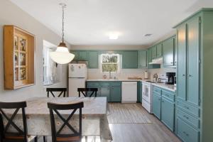 a kitchen with green cabinets and a table and chairs at A Special Retreat on a Mini-Farm -- in SMTX in San Marcos