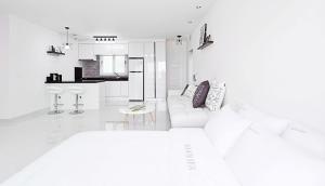 uma sala de estar branca com um sofá e uma cozinha em Glories Pension em Buan