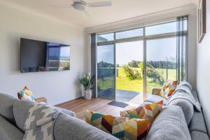 a living room with a couch and a large window at Beachside Cottage in Berrara