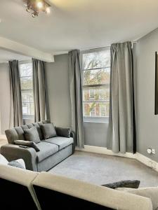 a living room with a couch and two windows at Comfortable flat in Stokes Croft in Bristol