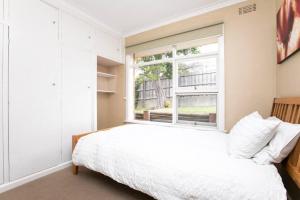 1 dormitorio con cama blanca y ventana en Comfortable Home with Wifi Parking & Views, en Royal Park