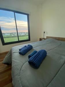 a large bed with two blue pillows on top of it at Dalcar Apart in Río Cuarto +16 photos