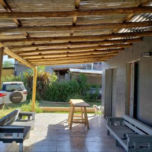 pérgola de madera en un patio con bancos y mesa en La Delia en Villa Rumipal