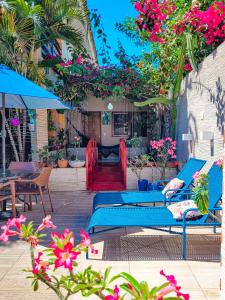 un patio con mesas azules, sillas y flores en Pousada Som dos Pássaros, en Porto de Galinhas