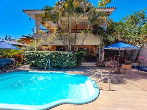 a swimming pool in front of a house at Pousada Som dos Pássaros in Porto De Galinhas