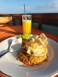 un plato de comida con un sándwich y un vaso de zumo de naranja en Maskot Penida Cottage, en Nusa Penida
