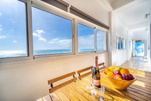 a table with a bowl of fruit and a bottle of wine at Oasis Noalys in Sardina