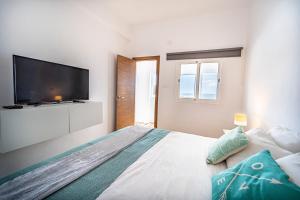 una camera con un grande letto e una TV a schermo piatto di Oasis Noalys a Sardina
