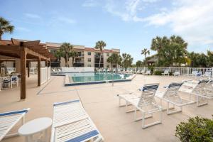 um pátio com cadeiras e uma piscina em Ocean Village Club Q11, 2 Bedrooms, Sleeps 6, Ground Floor, Pet Friendly em Saint Augustine
