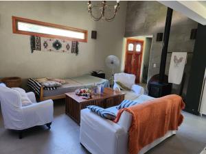 sala de estar con sillas blancas y mesa en La Delia en Villa Rumipal