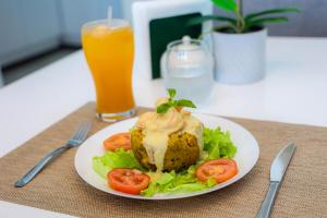 une assiette de nourriture avec des laitues et des tomates et un verre de jus d'orange dans l'établissement JOMYS HOTEL en Higüey, à Higuey