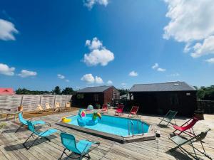 a backyard with a swimming pool with chairs and a pool slide at les gites du cocon in Cadet