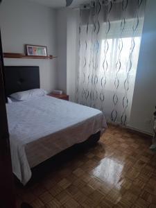 een slaapkamer met een bed en een raam met gordijnen bij Coslada parque blanco in Coslada