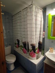 a bathroom with a toilet and a shower curtain with flowers at Coslada parque blanco in Coslada +3 photos