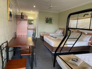 um quarto de hotel com 2 beliches e uma mesa em Yungaburra Park Motel em Yungaburra