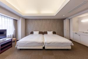 Habitación de hotel con 2 camas y TV en Court Hotel Asahikawa, en Asahikawa