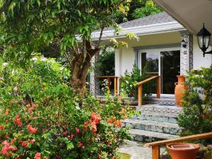 uma casa com flores e uma árvore no alpendre da frente em Garden Bungalows Resort em Siquijor