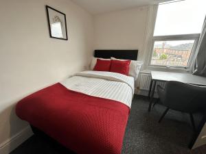 Un dormitorio con una cama roja y blanca y un escritorio. en Premier Nottingham Studios - Gawthorne en Nottingham