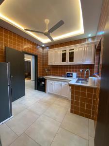 a kitchen with white cabinets and a ceiling fan at Cozy Lux Apartments by Harolty in Kumasi