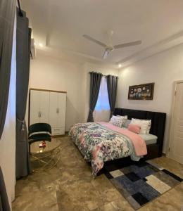 a bedroom with a bed and a chair at Cozy Lux Apartments by Harolty in Kumasi