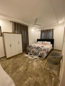a bedroom with a bed and a chair in it at Cozy Lux Apartments by Harolty in Kumasi