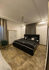 a bedroom with a large black bed and a chair at Cozy Lux Apartments by Harolty in Kumasi