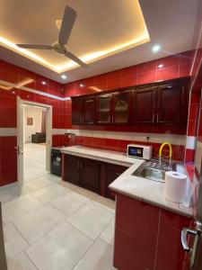 a kitchen with red walls and wooden cabinets at Cozy Lux Apartments by Harolty in Kumasi