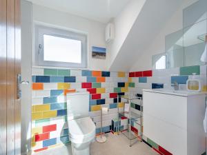 a bathroom with a toilet and colorful tiles on the wall at Postbox Cottage 