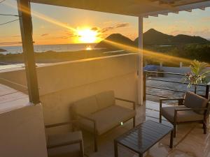 a sunset on a balcony with a couch and chairs at View Haven Villa in Jolly Harbour