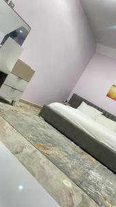 a white room with a bed and a staircase at Majorstone Luxury Apartment in Ibadan