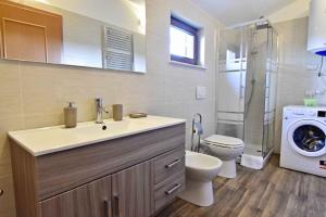 y baño con lavabo, aseo y lavadora. en Apartments for families with children Sosi, Umag - 22546, en Umag