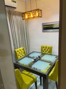 uma sala de jantar com uma mesa de vidro e cadeiras amarelas em Majorstone Luxury Apartment em Ibadan