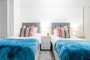 2 Betten in einem Schlafzimmer mit blauer und weißer Bettwäsche in der Unterkunft Food And Drink Expo 2024, Modern Large House, Minutes from the NEC - Airport Perfect for Contractors, HS2 Staff Fast WIFI AND FREE Parking in Birmingham