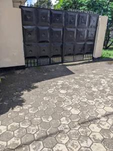 einen Zaun mit schwarzen Türen und einer Steinterrasse in der Unterkunft Cozy House, Quiet Area Kimandolu in Arusha