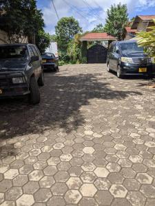 zwei Autos, die auf einer steinernen Einfahrt mit einem Schatten geparkt sind in der Unterkunft Cozy House, Quiet Area Kimandolu in Arusha