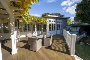 a patio with chairs and a table on a deck at By the Beach Coastal Cabin with Hot Tub in Cowes