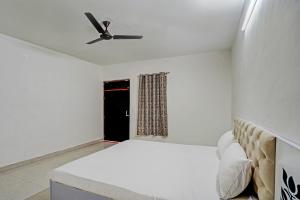 グルガオンにあるSuper OYO Chawla's Hotel & Restaurantの白いベッドルーム(ベッド1台、天井ファン付)